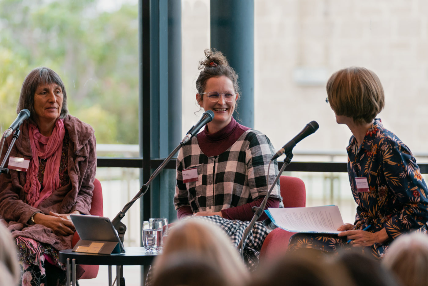 Image of three women smiling while seated in front of microphones