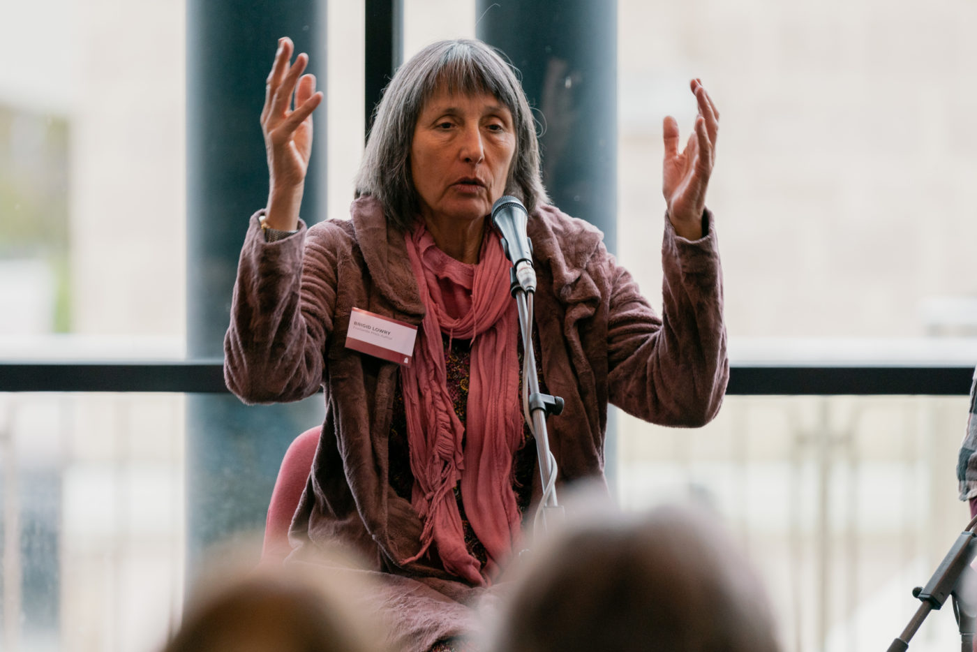 Image of a woman speaking into a microphone with her arms above her head