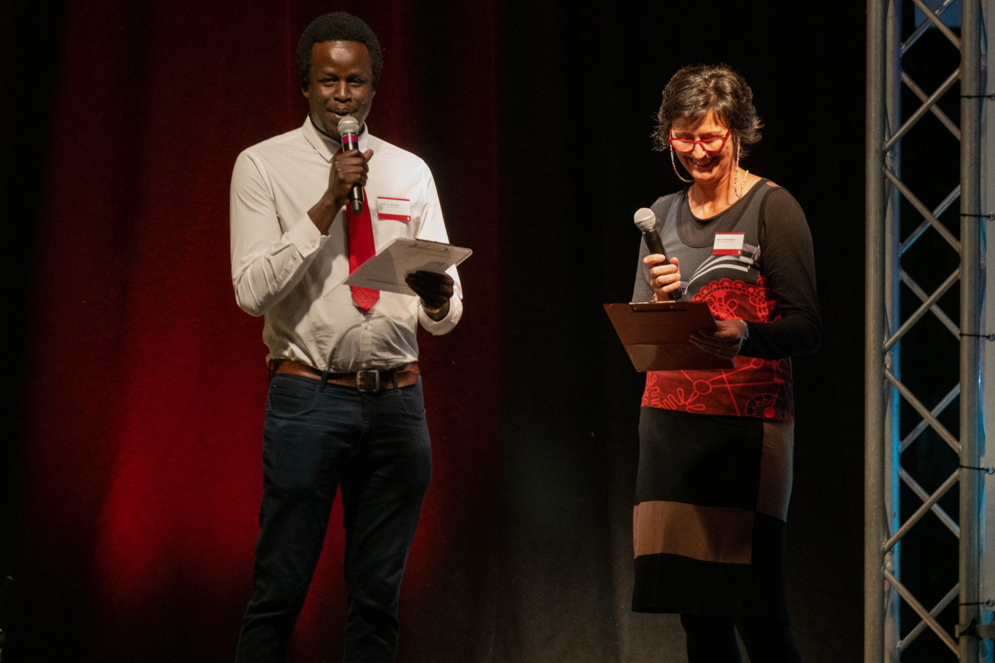 Author Yuot A Alaak holding a microphone standing next to author Deb Fitzpatrick holding a microphone.