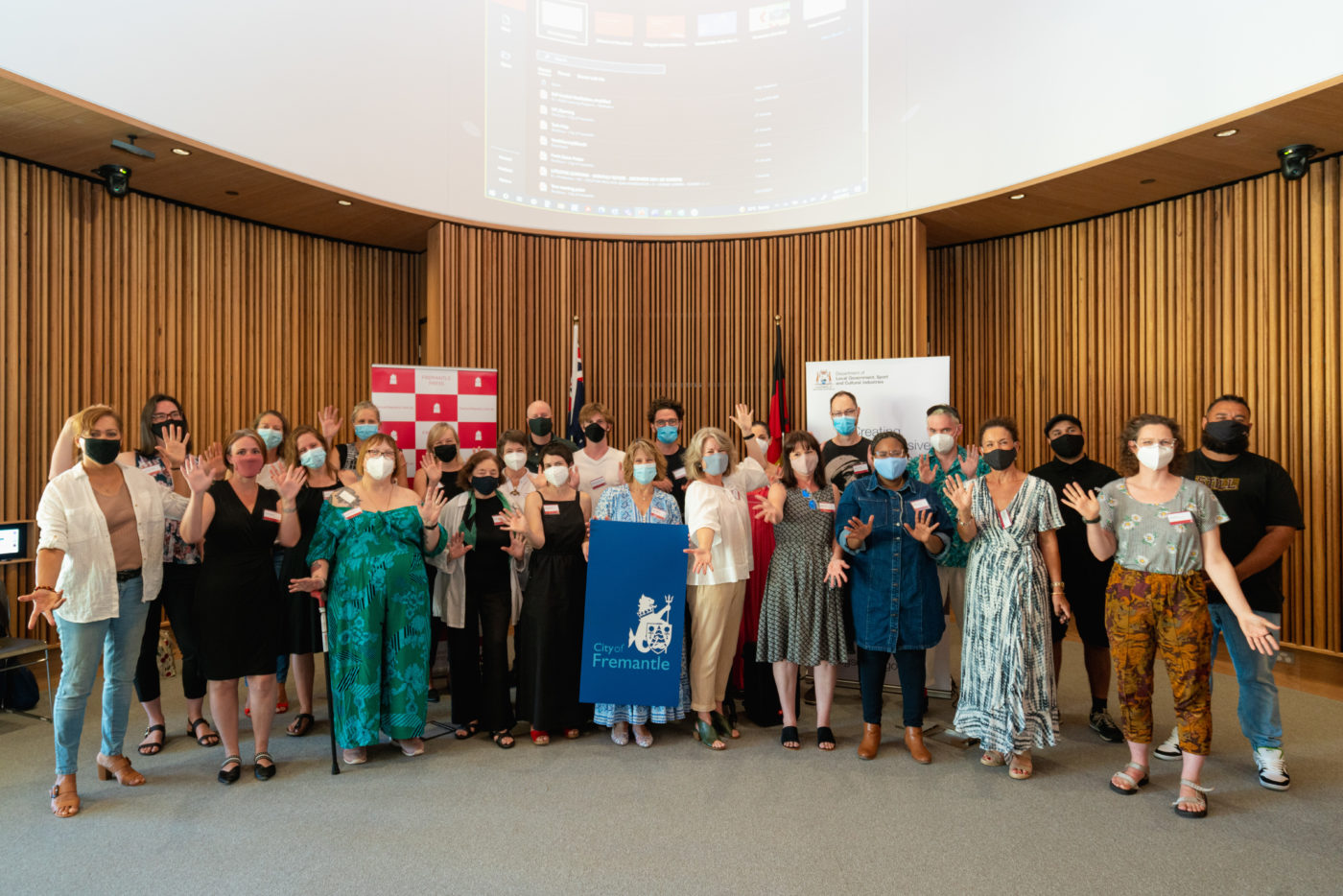 Fremantle Press authors stand side by side waving their hands in the air smiling