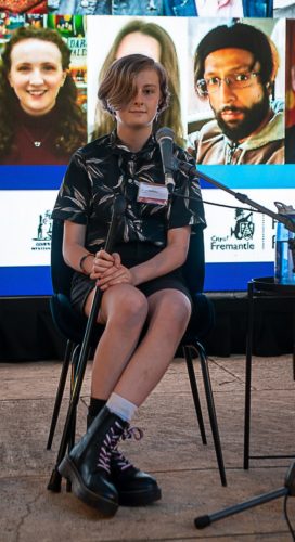 Riley Benfell in front of the microphone at the business of being a writer