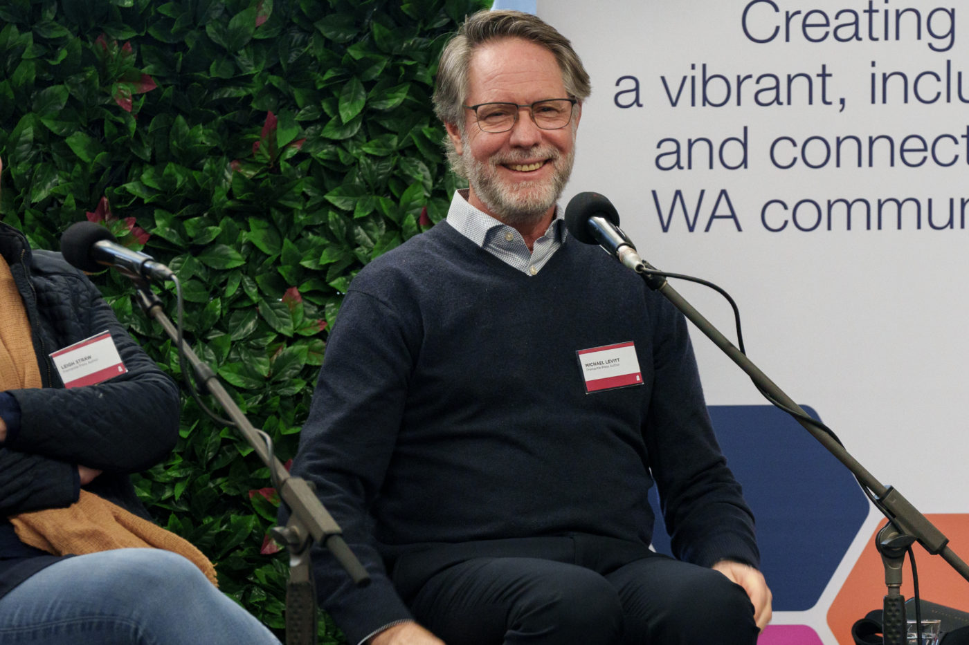 Michael Levitt smiling at the crowd while seated on the panel